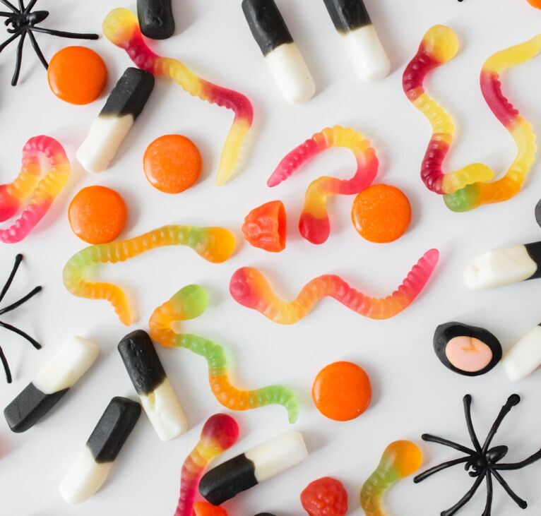 halloween, junk food and confectionery concept concept - multicolored gummy worms and jelly candies over white background